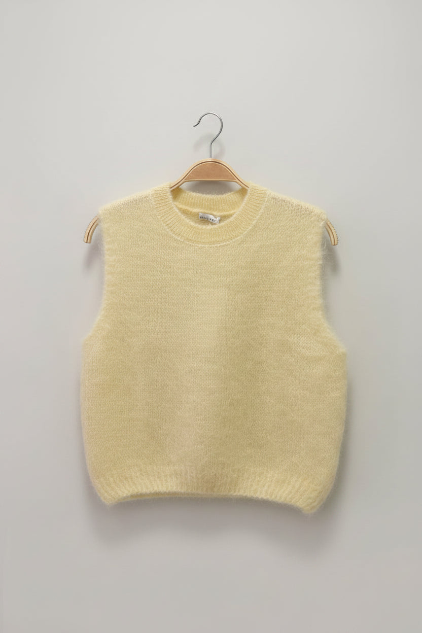 Light yellow sweater on a hanger against a plain background