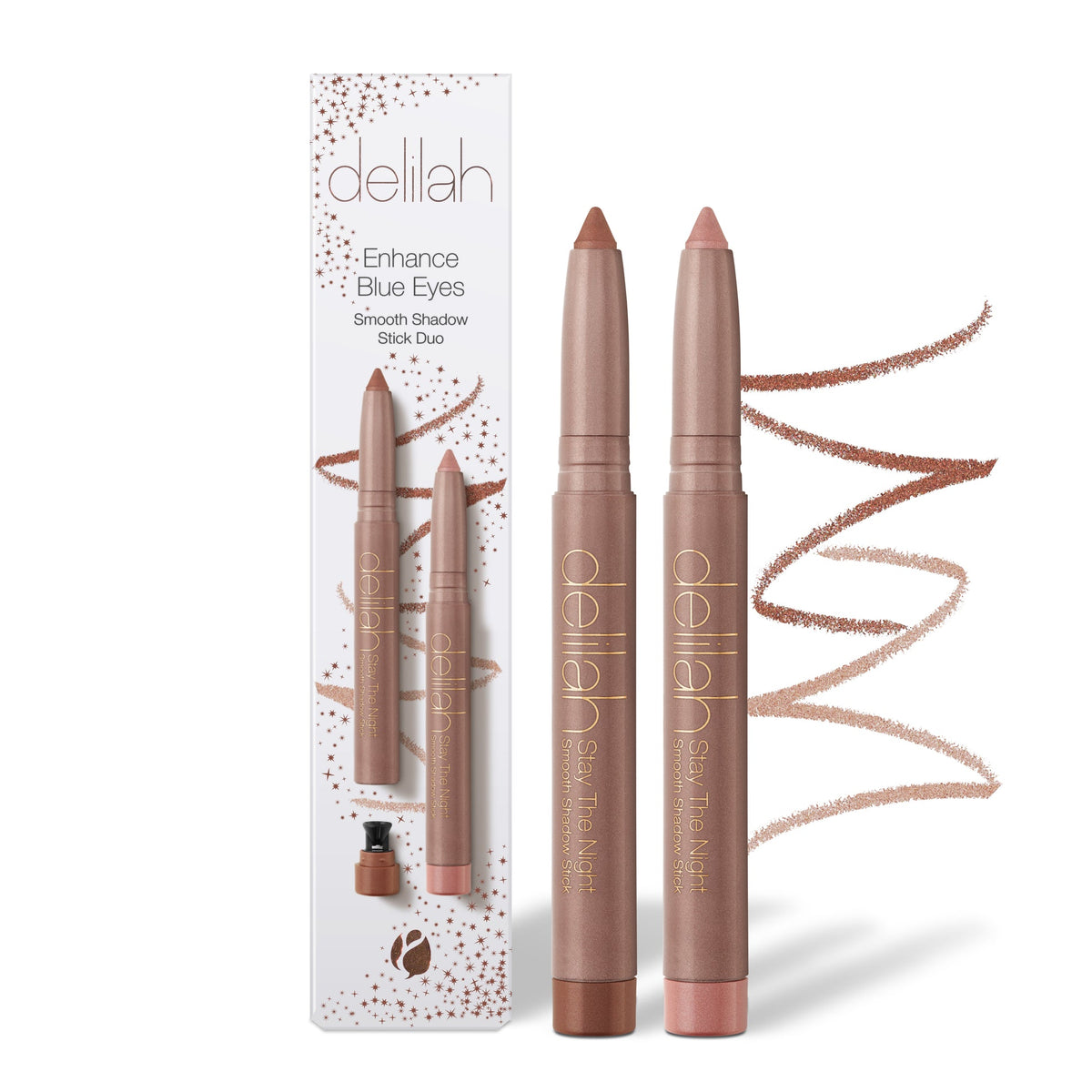 A Delilah Enhance Blue Eyes Smooth Shadow Stick Duo set, featuring two makeup sticks in a warm taupe-brown shade next to their white and gold packaging box, with swatches of the shadow color on the right.