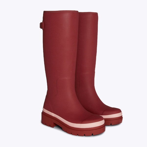 Merry People Fergie Tall Wellies in Beetroot Red - a pair of knee-high matte red rubber rain boots with chunky platform soles and a contrasting light pink stripe near the toe, shown against a plain white background.