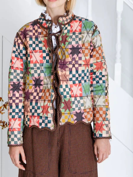 Person wearing a colorful geometric-patterned jacket with a white background