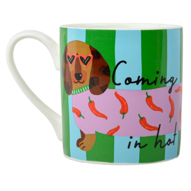 A white ceramic mug featuring a whimsical dachshund illustration wearing heart-shaped sunglasses and a pink sweater with red chili peppers, set against green and light blue vertical stripes. The text 'Coming in hot' is written in black script on the right side.