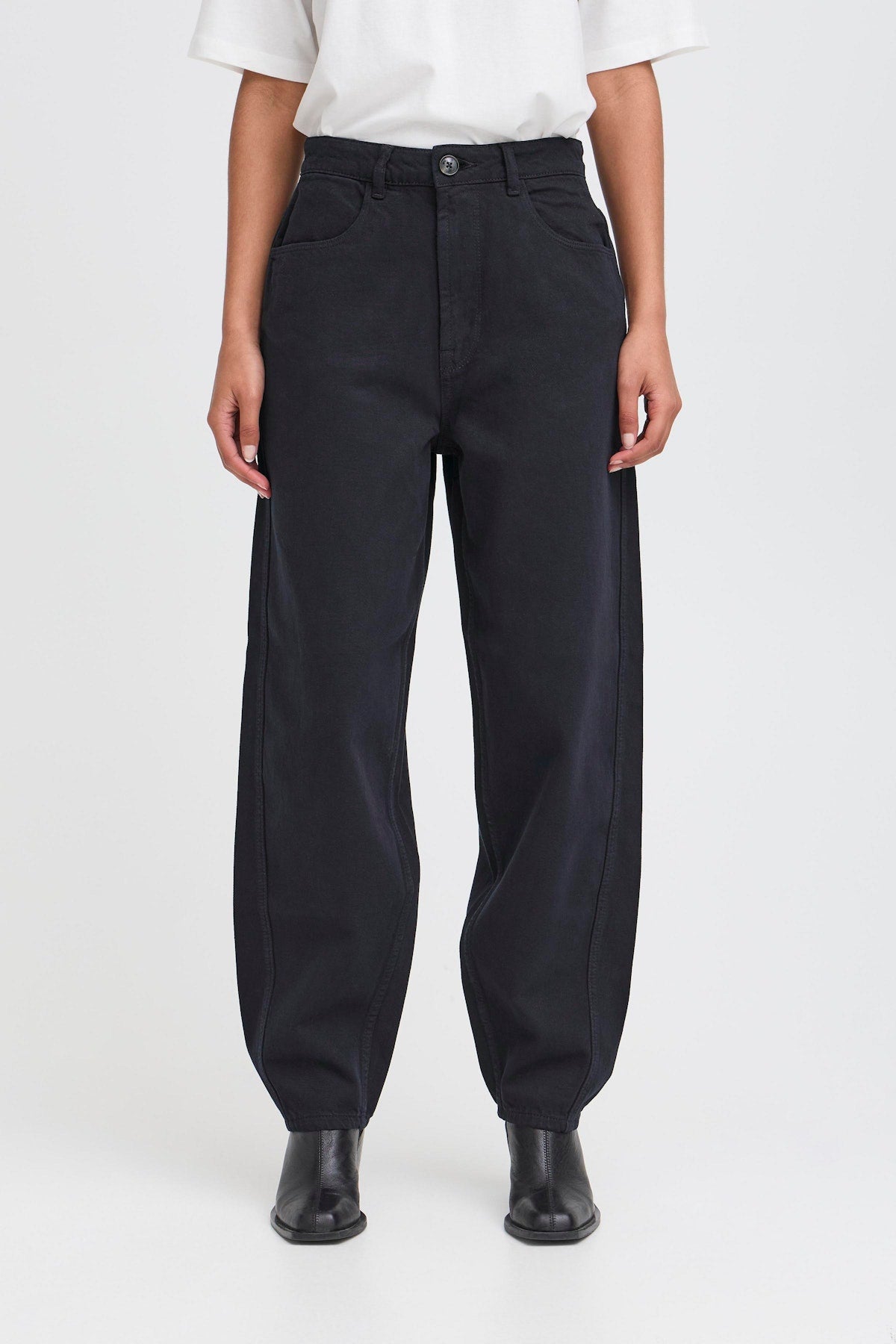 ICHI Hezano Jeans in Dark Navy. Person wearing black pants and white shirt on a white background