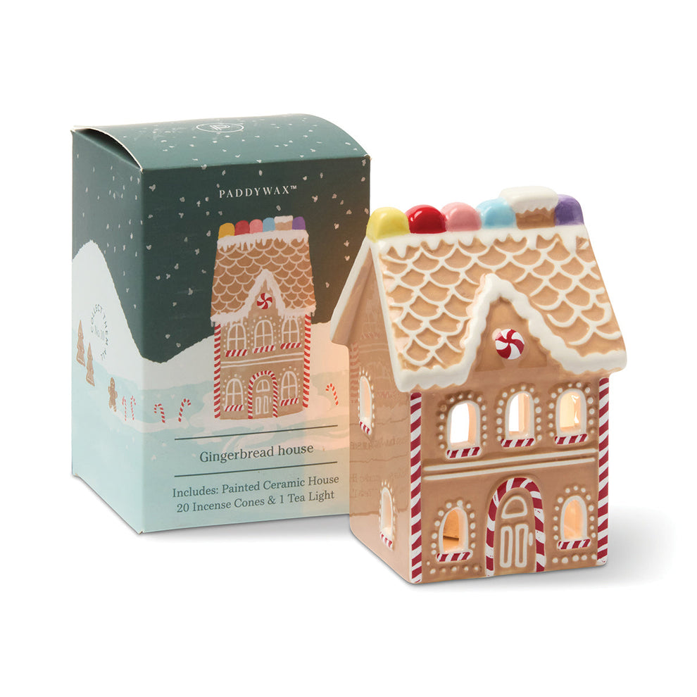 Gingerbread house-shaped candle with decorative box on a white background