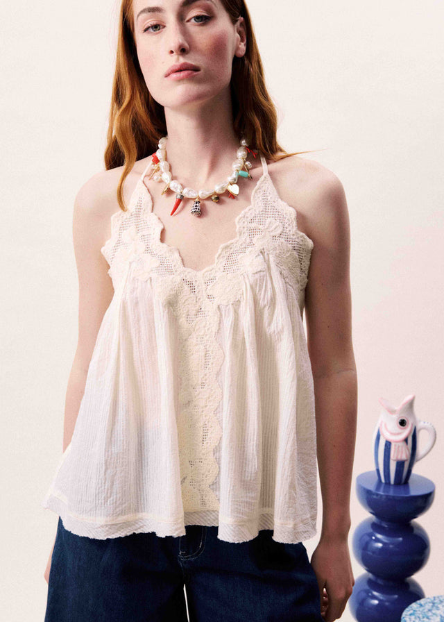 Woman wearing a white lace top with a plain background
