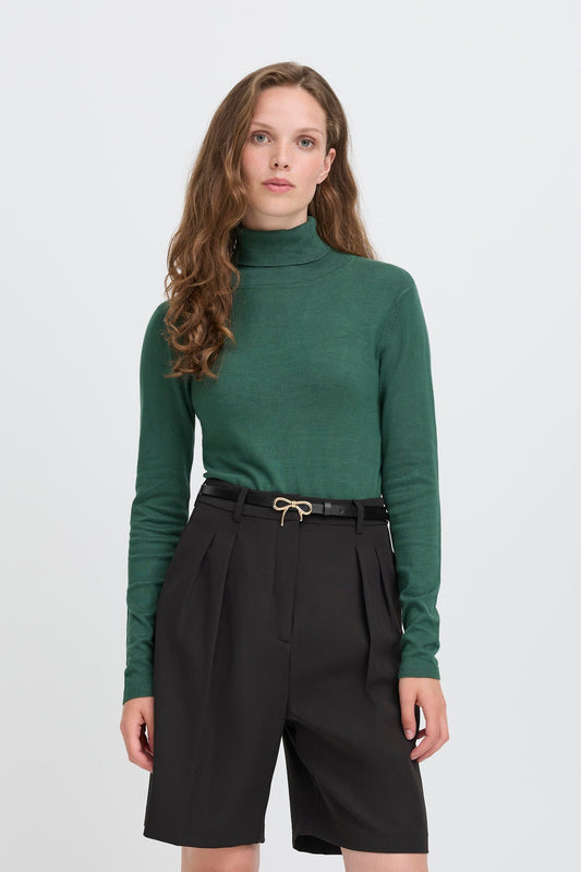 Ichi Ollin Belt in Black. Woman wearing a green turtleneck and black shorts on a white background