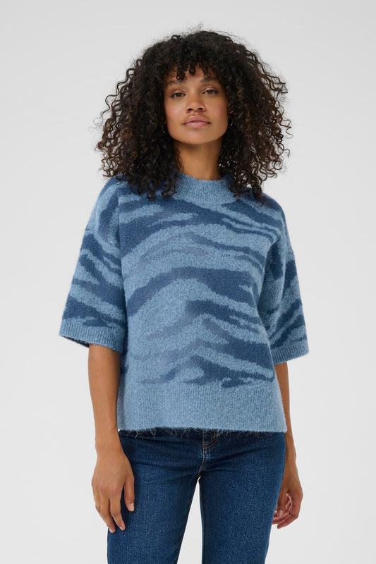 KAFFE Sandra Pullover in Windward Blue/Bering Sea Animal. Woman wearing a blue patterned sweater and jeans on a white background