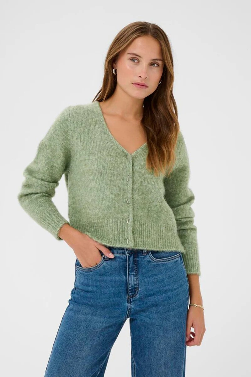 Woman wearing a green cardigan and blue jeans on a white background