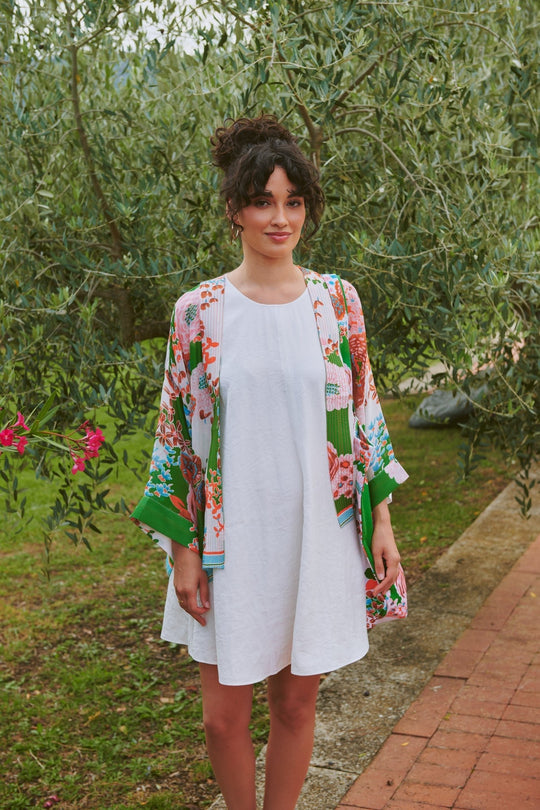 Woman wearing a white dress with a colorful floral kimono in an outdoor setting