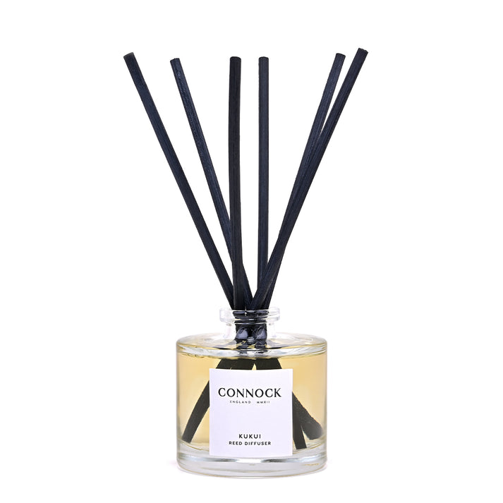 Connock London Kuskii Reed Diffuser with a clear glass bottle, pale amber liquid, and six black reeds, shown on a white background.