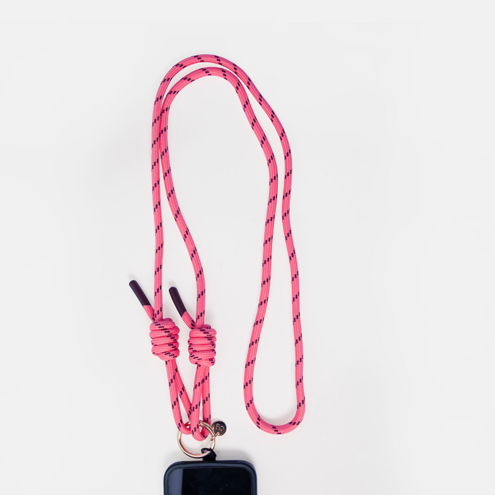 A pink braided rope phone strap with black knots and a small metal ring, shown against a plain white background with a black phone partially visible at the bottom.