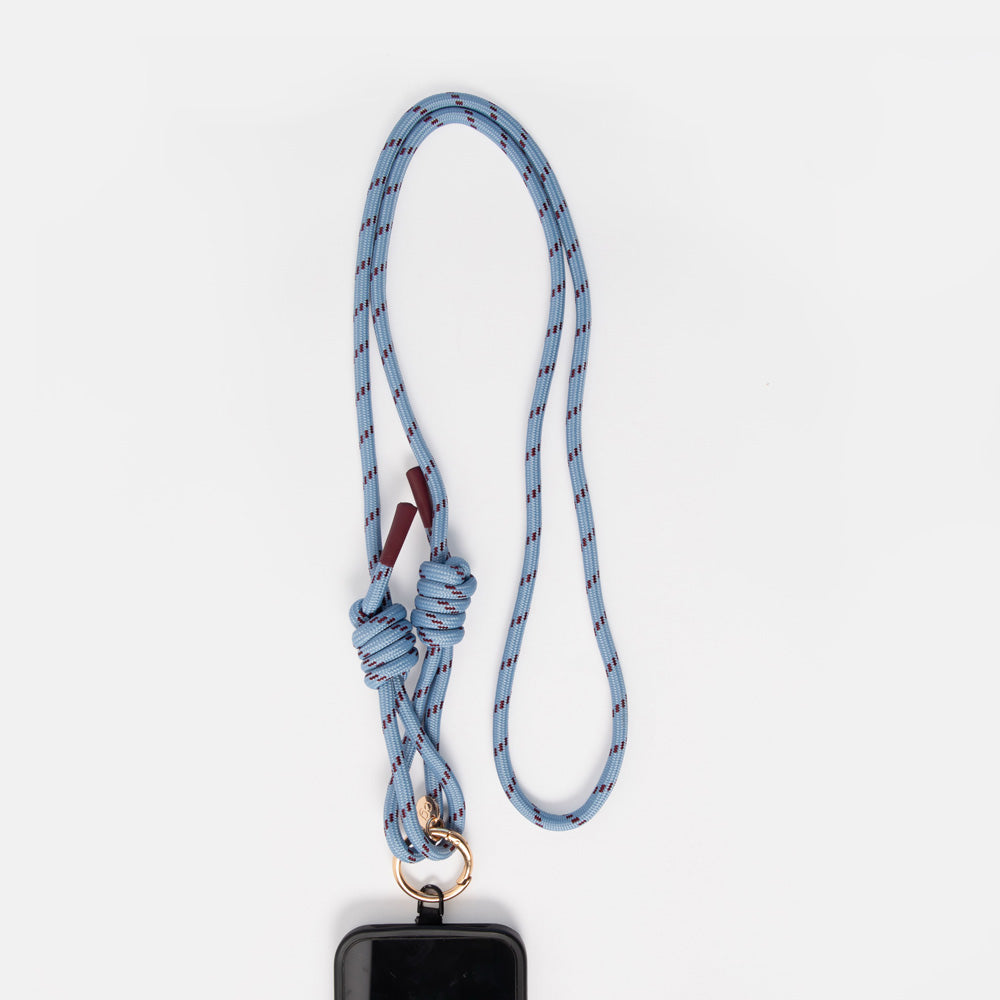 A light blue braided cord phone strap with a knotted detail, gold metal ring, and a black phone case attached, shown against a plain white background.
