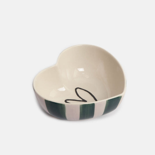 A heart-shaped ceramic bowl with a cream-colored interior and exterior, featuring dark green and cream vertical stripes on the outside and a black line-art heart design inside.