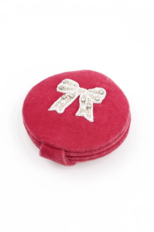 Red round jewelry box with a decorative bow on a white background