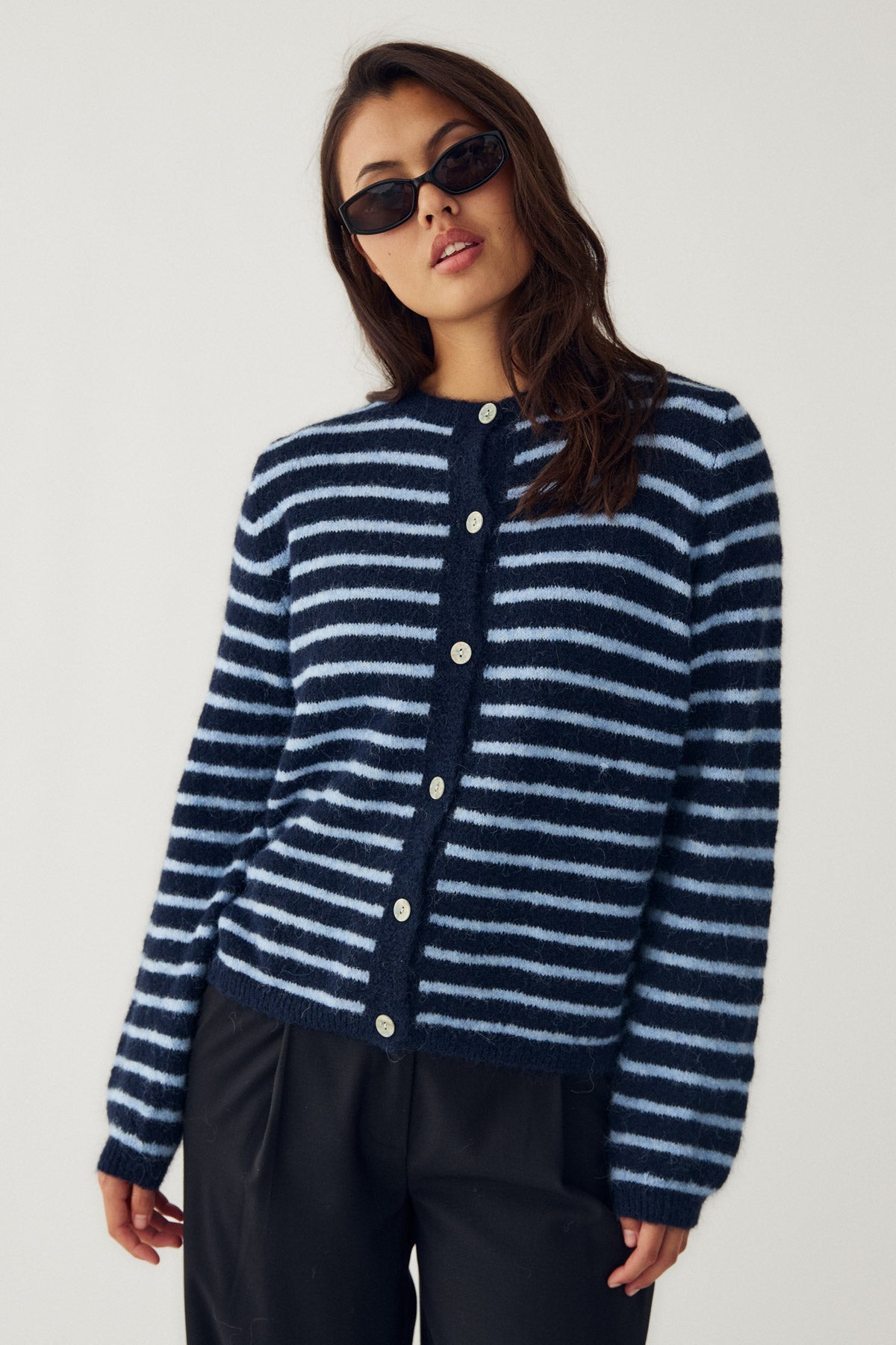 Woman wearing a blue and white striped cardigan on a plain background