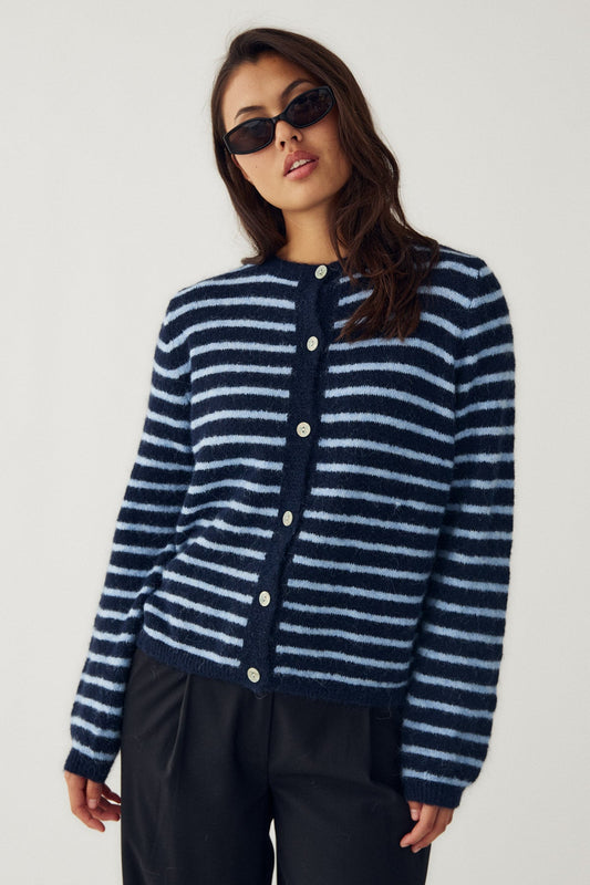 Woman wearing a blue and white striped cardigan on a plain background