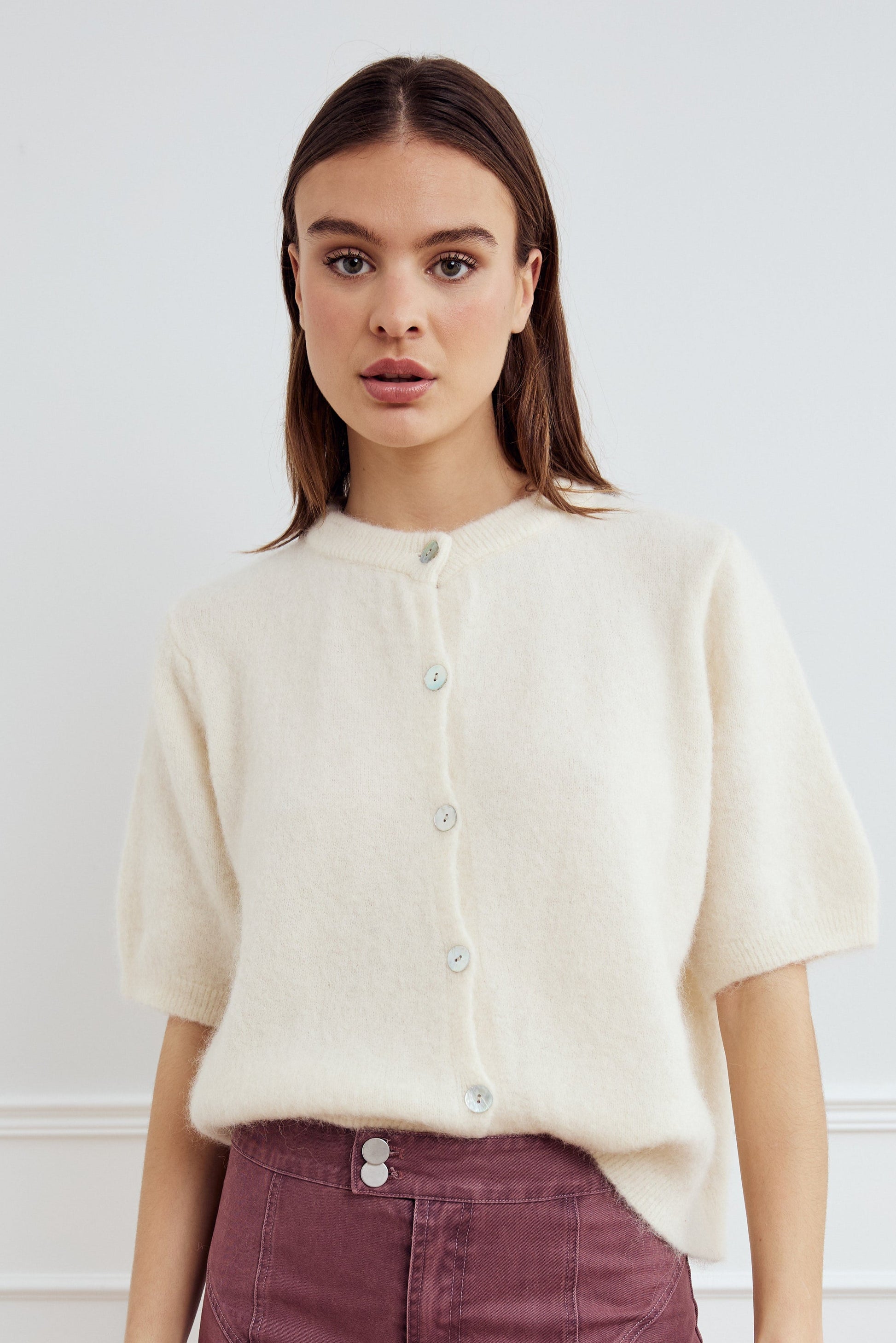 Noella Kae SS Knit Cardigan in Oyster. Woman wearing a cream-colored cardigan against a white background