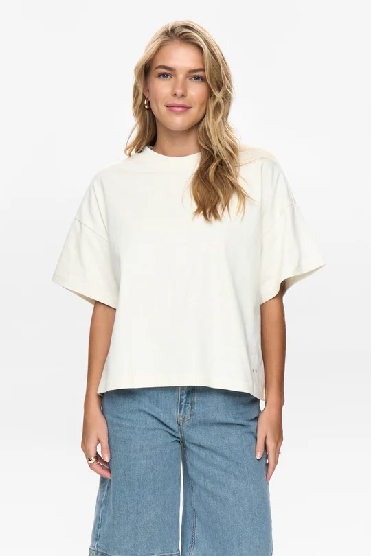 Woman wearing an off white oversized t-shirt and blue jeans on a white background
