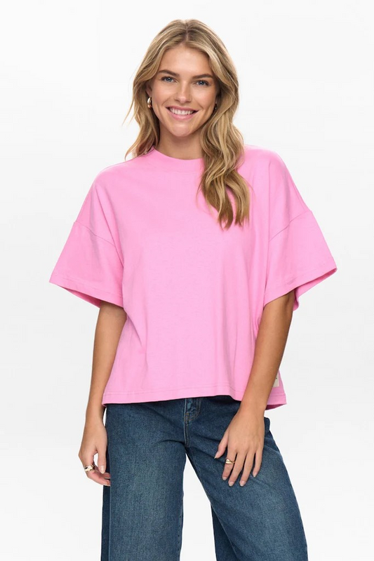 Woman wearing a pink oversized t-shirt and blue jeans on a white background