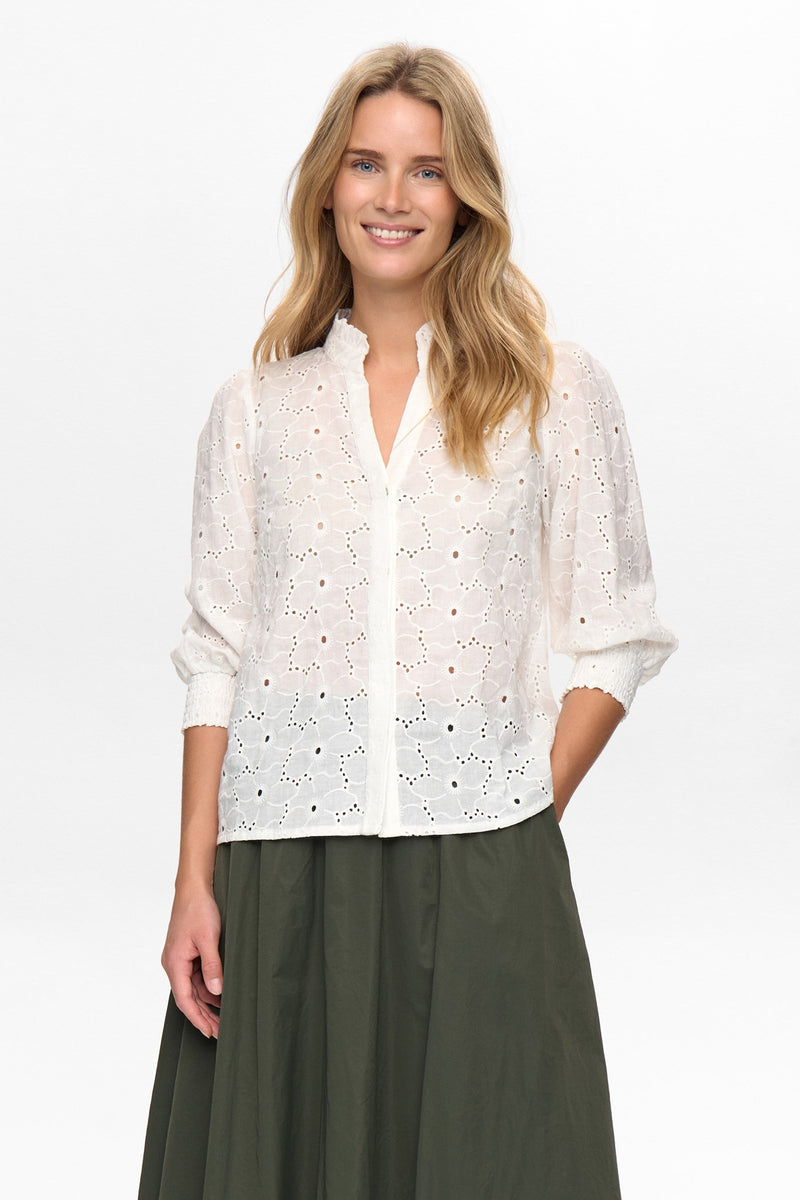 Woman wearing a white lace blouse and green skirt on a white background