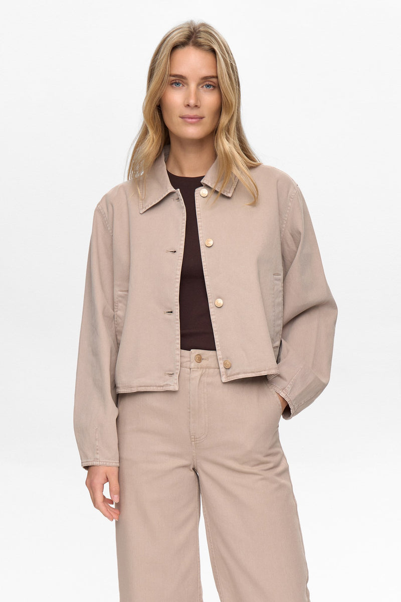 Woman wearing a beige jacket and pants on a white background