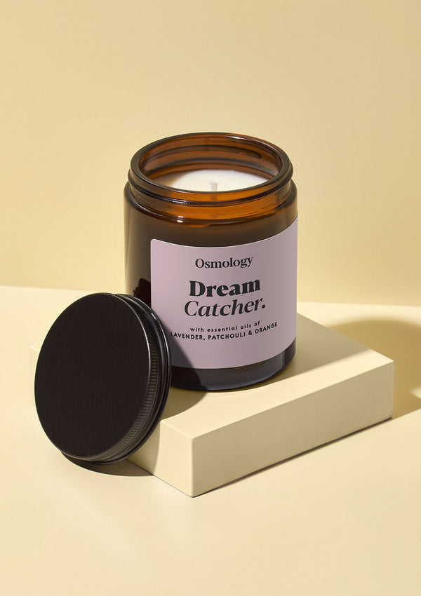 Osmology Dream Catcher candle with a black lid on a beige background