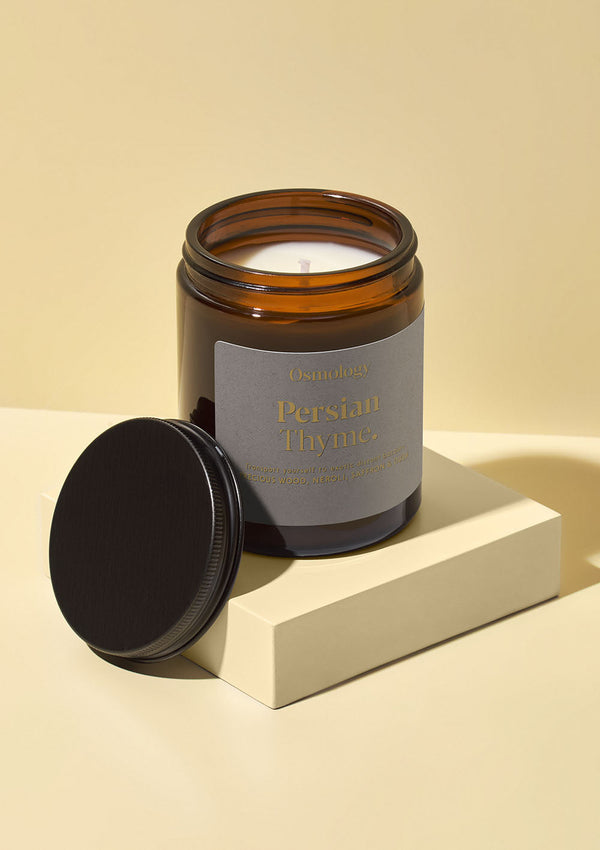 Amber glass candle with a label on a beige background