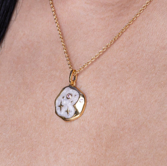 Gold necklace with a pendant on a person's neck