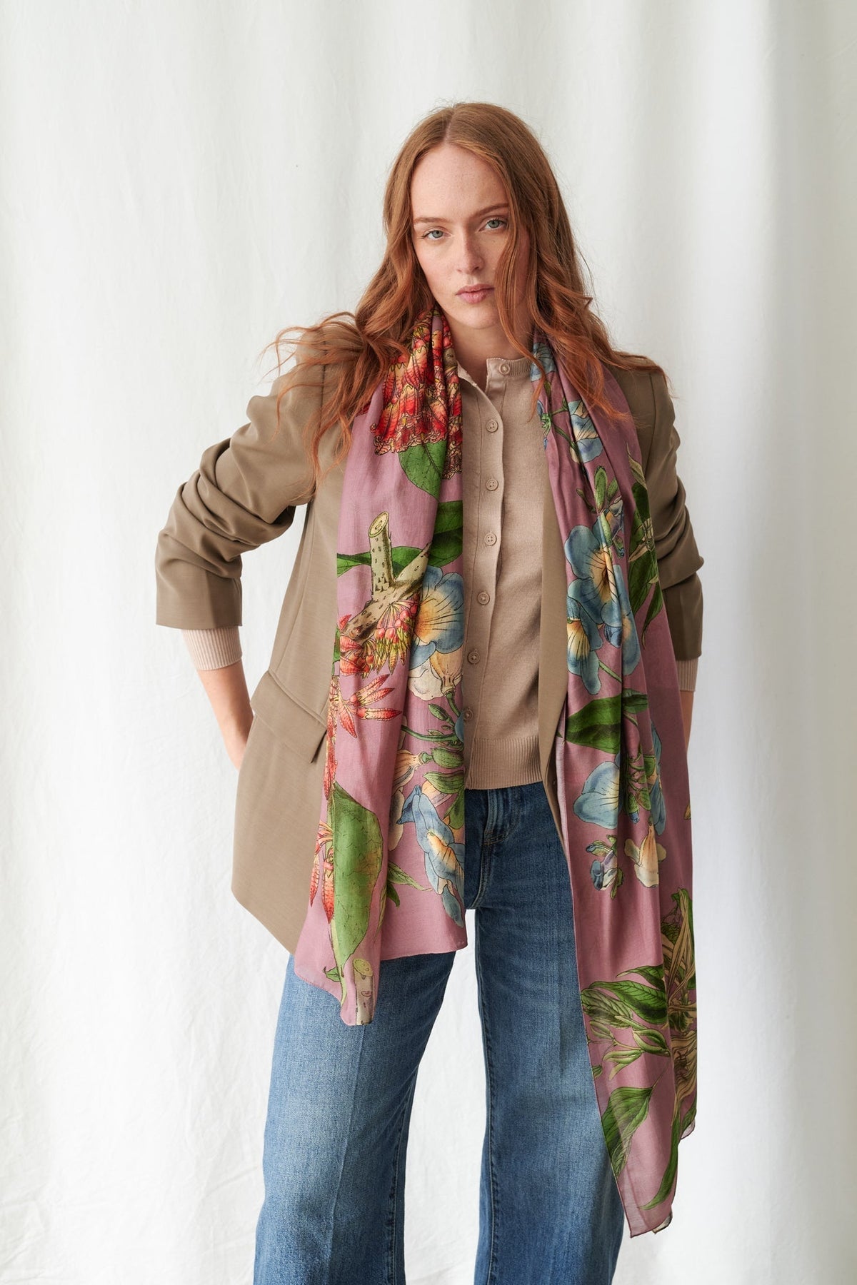 Woman wearing a colorful floral scarf with a neutral background