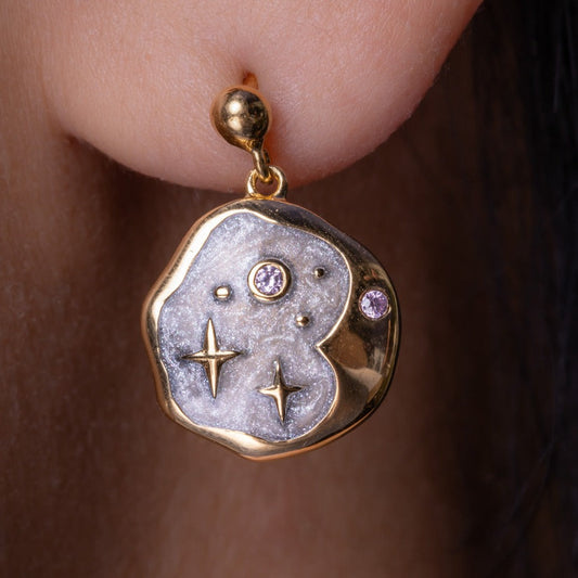 Gold earring with star and gemstone design worn on an ear