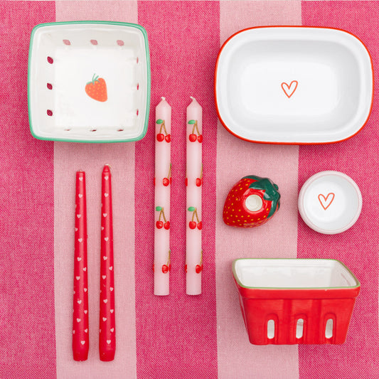 Table setting with red and white ceramic items on a pink checkered tablecloth