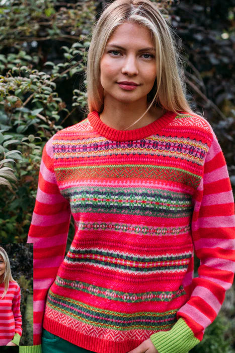 Woman wearing a colorful striped sweater with a patterned design, standing outdoors.