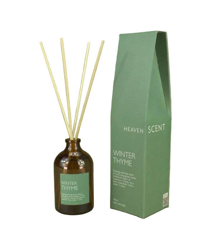 Winter Thyme reed diffuser set with an amber glass bottle, four natural reed sticks, and a tall sage green box labeled Heaven Scent, set against a solid olive green background.
