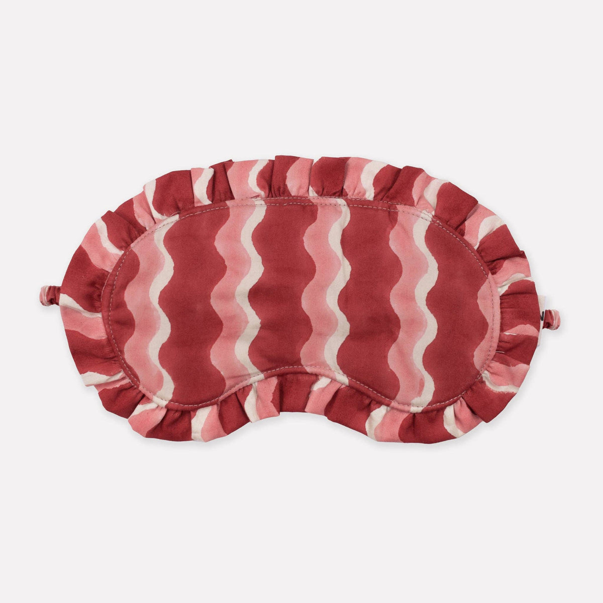 Red and white striped eye mask on a light beige background