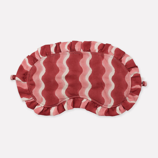 Red and white striped eye mask on a light beige background