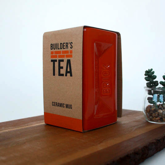 Red ceramic mug with 'Builder's Tea' packaging on a wooden surface