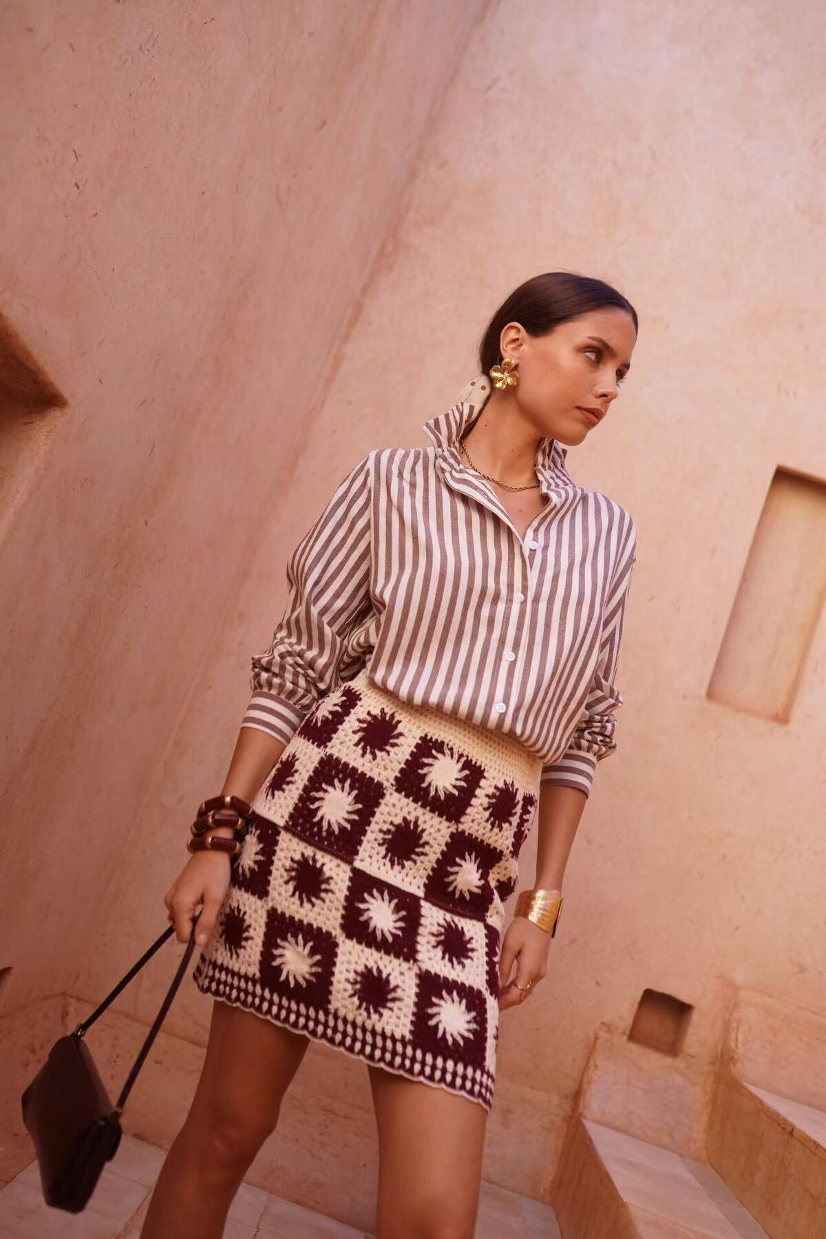 Woman wearing a striped shirt with frill neck and patterned skirt in a desert setting