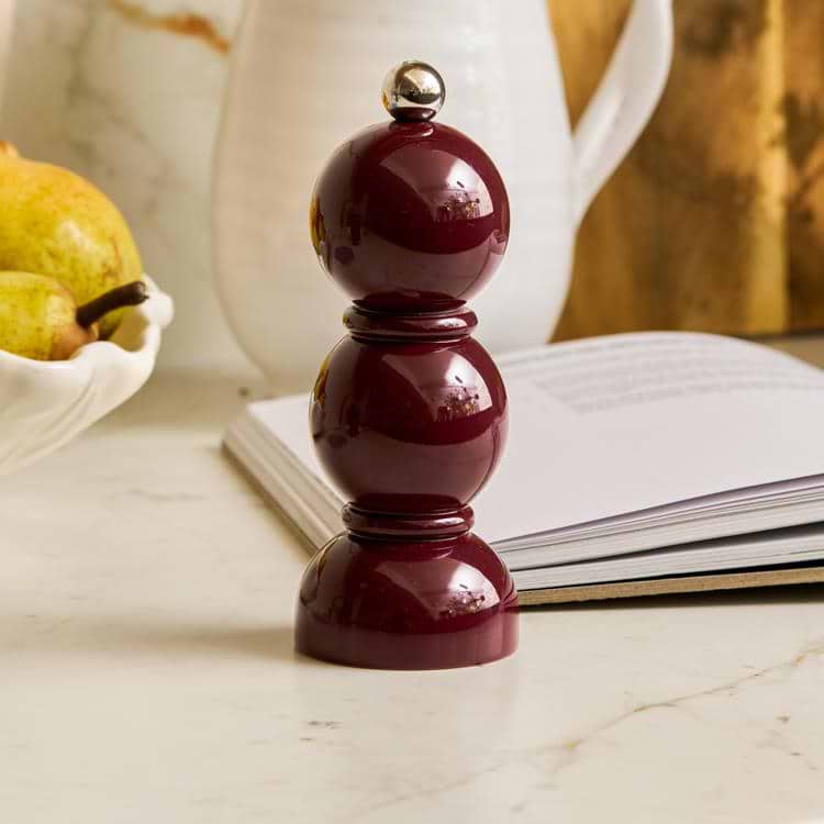 Cherry pepper grinder on a marble surface with a book and pears in the background