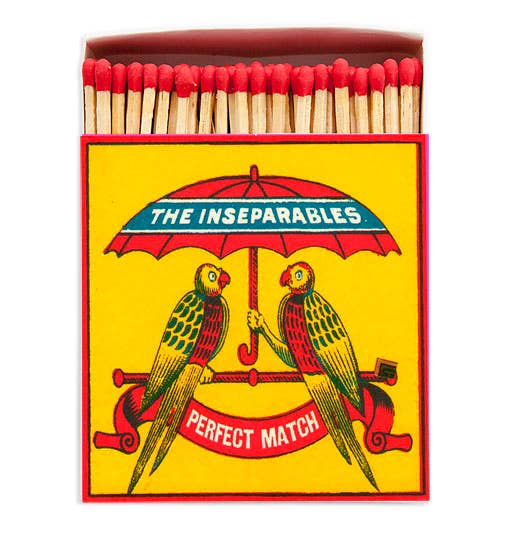 Matchbox with 'The Inseparables' design featuring two parrots under an umbrella.