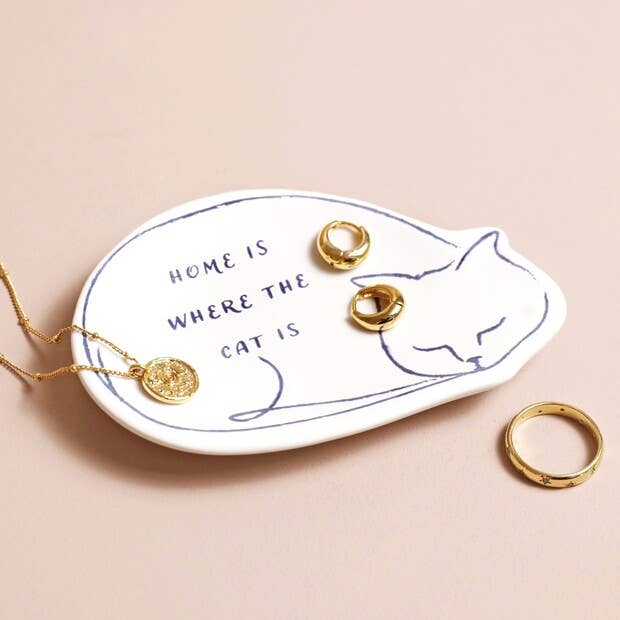 Trinket dish with cat design and jewelry on a beige background