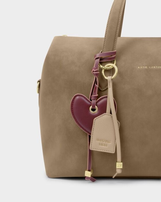 Brown handbag with a heart-shaped keychain on a light gray background