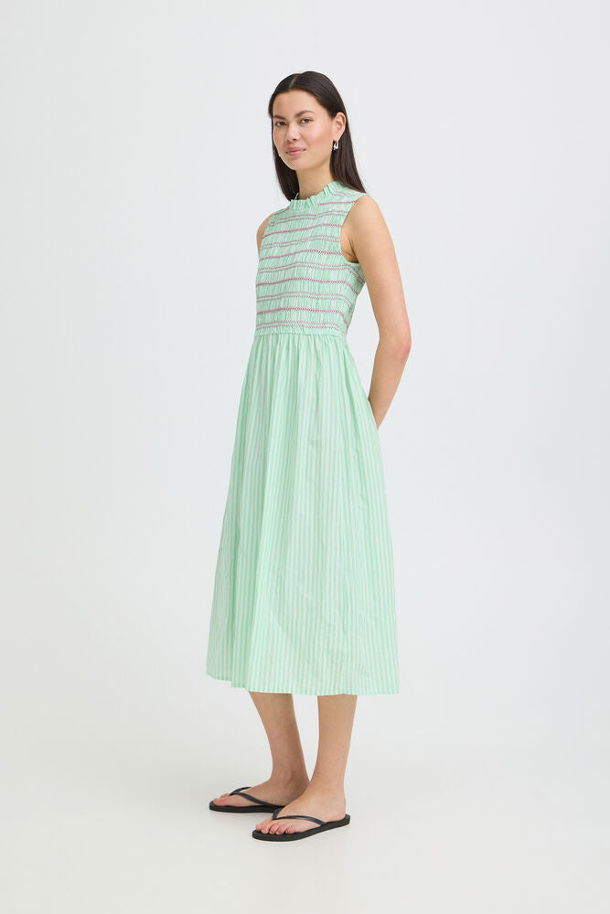 Woman wearing a light green dress with vertical stripes on a white background