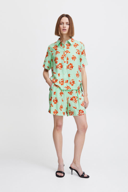 Ichi Yasma Shorts in Sprucestone, a pale green short with a bright berry print in orange