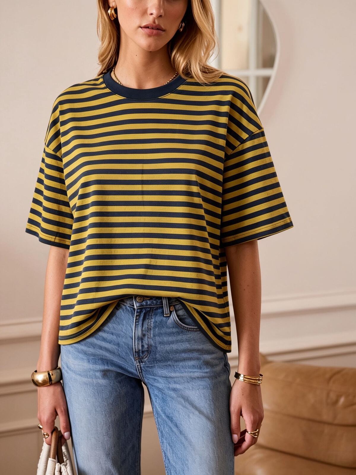 Woman wearing a yellow and navy striped shirt with blue jeans indoors.